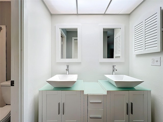 full bathroom featuring double vanity, toilet, and a sink