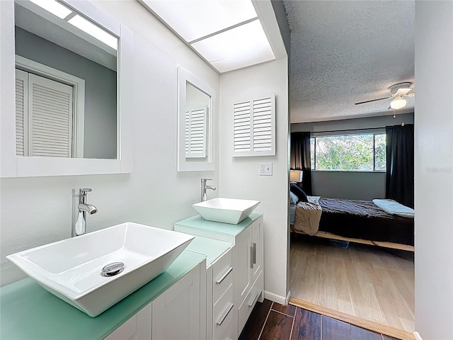 bathroom with wood finished floors, baseboards, ceiling fan, ensuite bathroom, and a textured ceiling