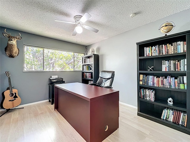 office space featuring a textured ceiling, light wood-style floors, baseboards, and ceiling fan