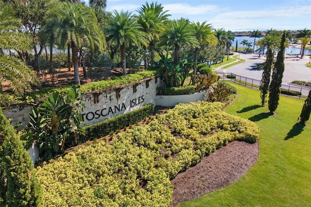 community / neighborhood sign featuring a water view, a lawn, and fence