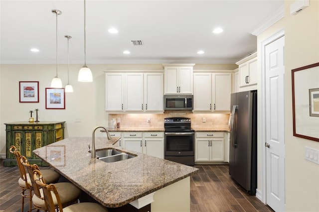 kitchen with visible vents, a breakfast bar, a sink, stainless steel appliances, and backsplash