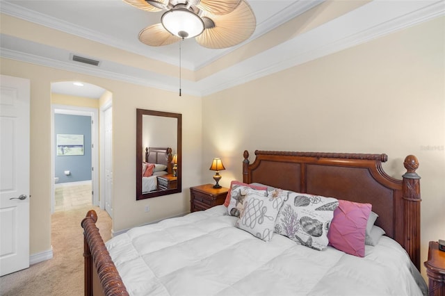 bedroom with visible vents, crown molding, light colored carpet, a tray ceiling, and arched walkways