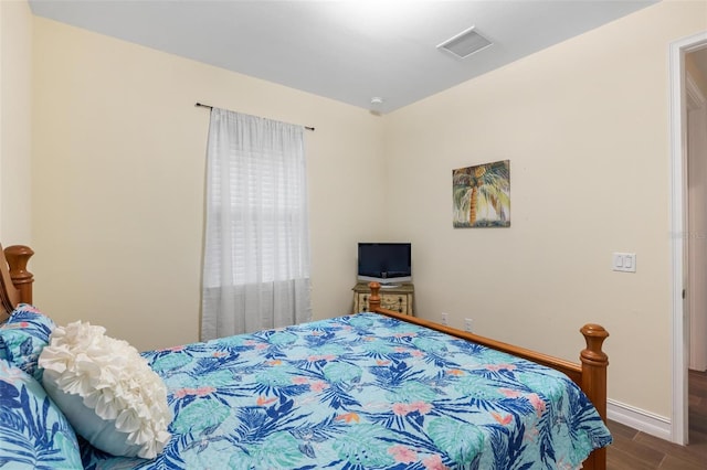 bedroom with visible vents, baseboards, and wood finished floors