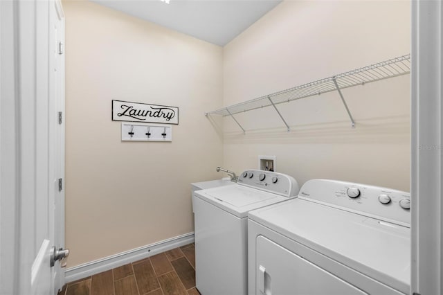 clothes washing area featuring washer and dryer, baseboards, wood finish floors, and laundry area