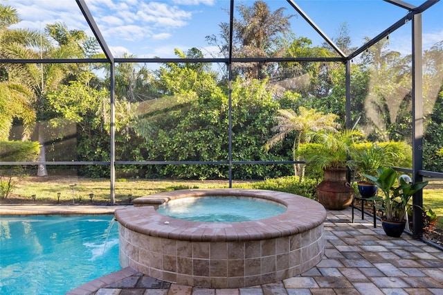 outdoor pool with glass enclosure, an in ground hot tub, and a patio area