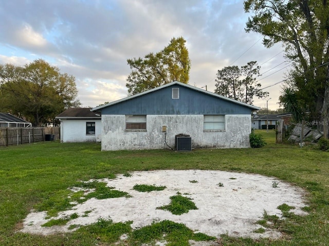 rear view of property with central AC, a yard, and fence