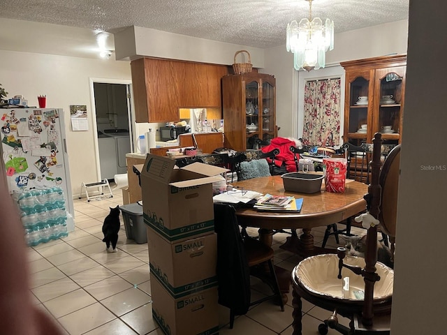 dining room with light tile patterned flooring, a notable chandelier, washer and dryer, and a textured ceiling