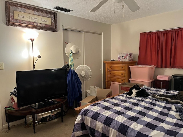 carpeted bedroom with a ceiling fan, visible vents, a closet, and a textured ceiling