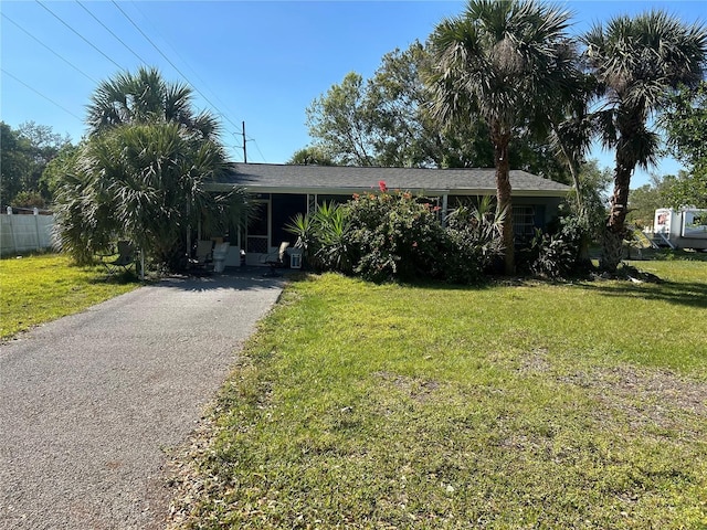 view of front of home featuring aphalt driveway, fence, and a front lawn