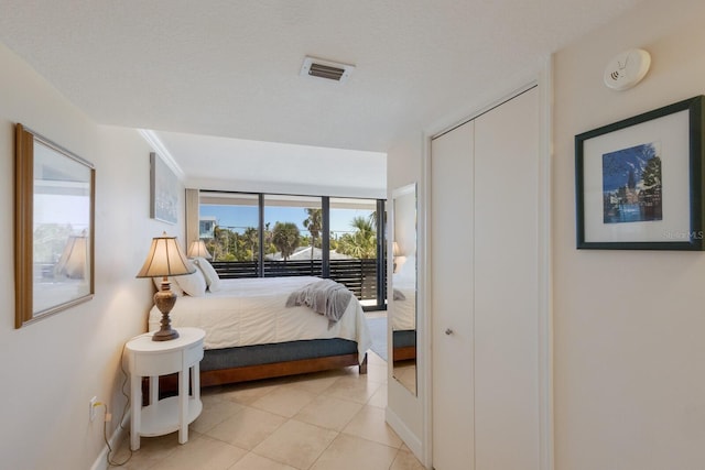 bedroom featuring access to exterior, visible vents, baseboards, light tile patterned floors, and a closet