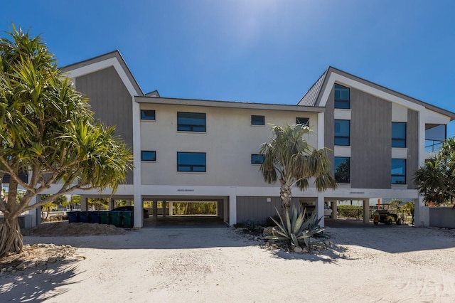 view of building exterior featuring a carport and dirt driveway