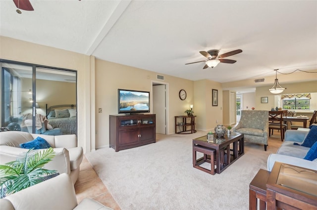 living area featuring visible vents, light colored carpet, and ceiling fan