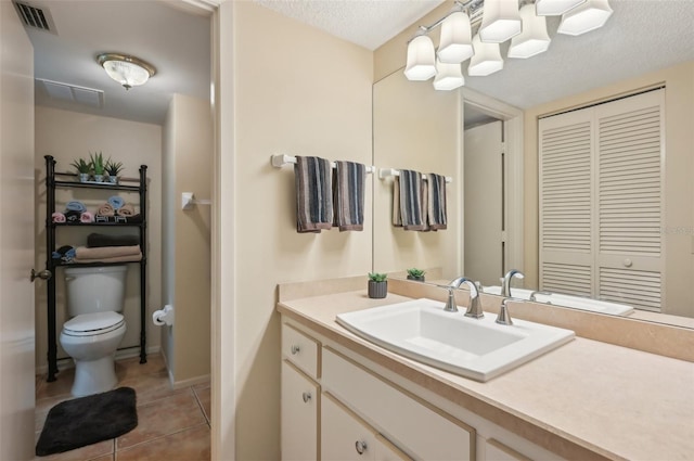 bathroom featuring visible vents, toilet, vanity, tile patterned floors, and a textured ceiling