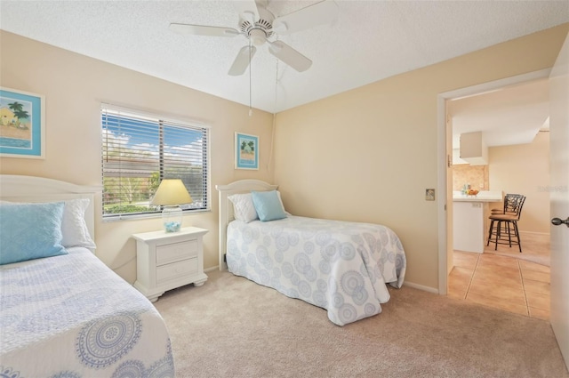 bedroom with baseboards, ceiling fan, light colored carpet, light tile patterned floors, and a textured ceiling