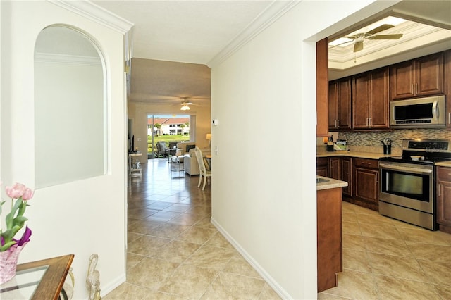 hallway featuring light tile patterned floors, baseboards, and ornamental molding