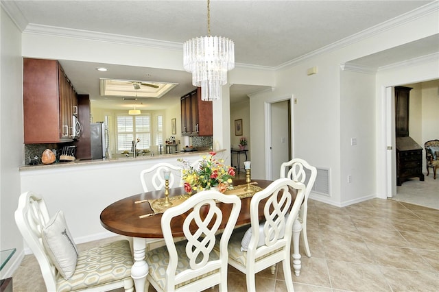 dining room with light tile patterned floors, baseboards, visible vents, ornamental molding, and a raised ceiling