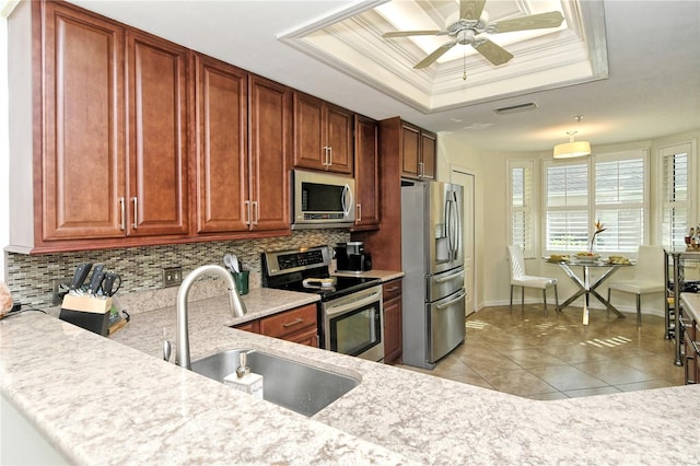 kitchen with a sink, stainless steel appliances, light countertops, crown molding, and a raised ceiling