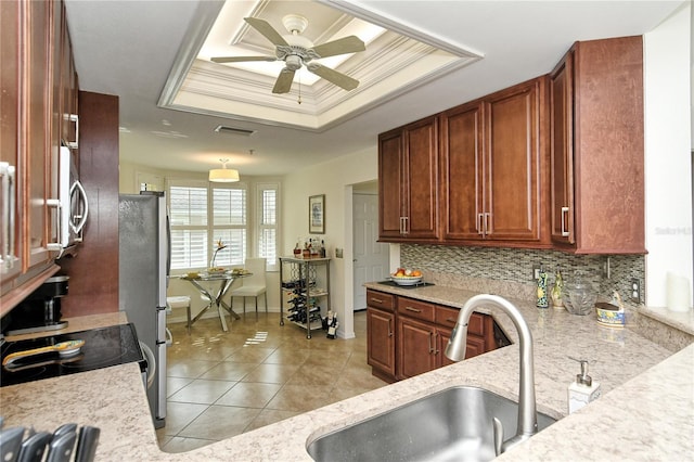 kitchen with ceiling fan, a sink, crown molding, a raised ceiling, and tasteful backsplash