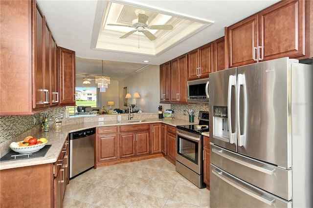 kitchen featuring ceiling fan, stainless steel appliances, a tray ceiling, and a sink