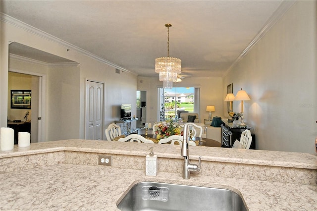 kitchen featuring a chandelier, open floor plan, crown molding, and a sink