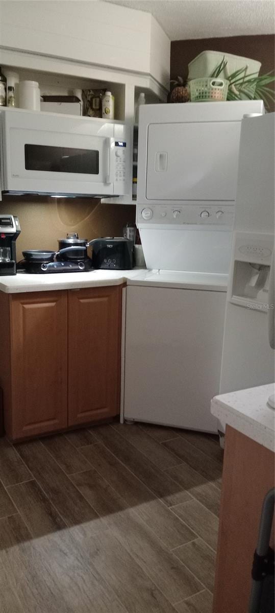 kitchen with white microwave, wood tiled floor, open shelves, light countertops, and stacked washer / dryer