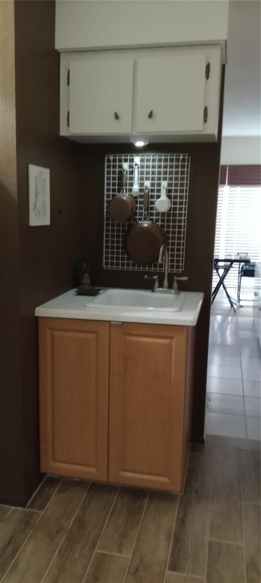 kitchen with white cabinetry, light countertops, wood tiled floor, and a sink