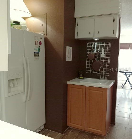 722 S Blvd Of The Presidents Unit 201, Sarasota, FL 34236 - kitchen featuring white refrigerator with ice dispenser, a sink, light countertops, and white cabinetry