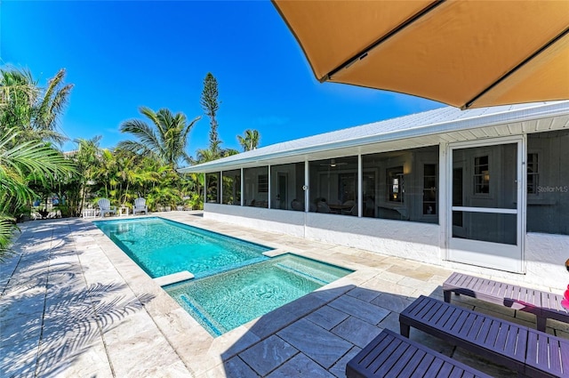 view of swimming pool featuring a pool with connected hot tub, a patio area, and a sunroom