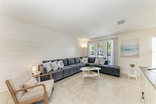 living room featuring visible vents, wood walls, and baseboards