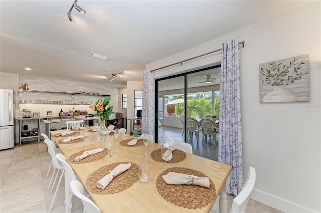 dining area featuring light tile patterned floors, rail lighting, and baseboards