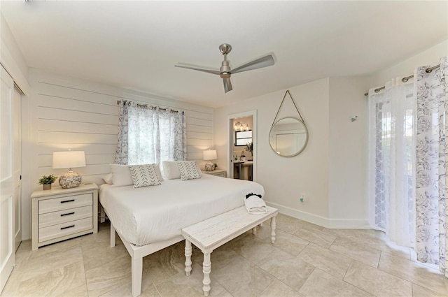 bedroom with baseboards, ensuite bath, and ceiling fan