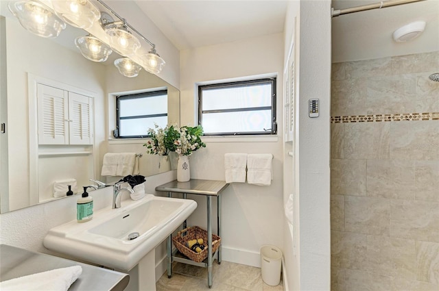 bathroom featuring a sink, tile patterned floors, baseboards, and tiled shower