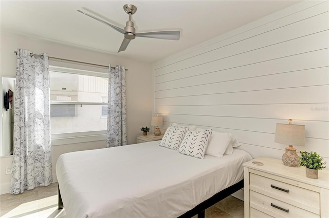 bedroom featuring wooden walls and a ceiling fan