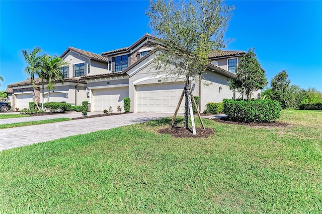 view of front facade with a front yard, an attached garage, stucco siding, a tiled roof, and decorative driveway