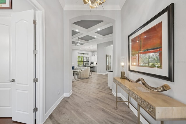 hallway with wood finished floors, baseboards, coffered ceiling, arched walkways, and beamed ceiling