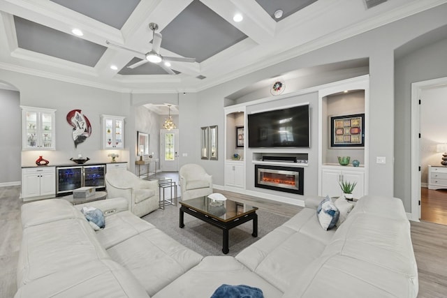 living room featuring arched walkways, a glass covered fireplace, wine cooler, and light wood-style floors