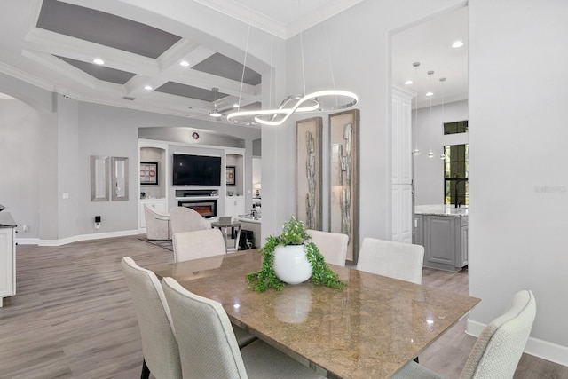 dining space with baseboards, coffered ceiling, arched walkways, light wood-style floors, and crown molding