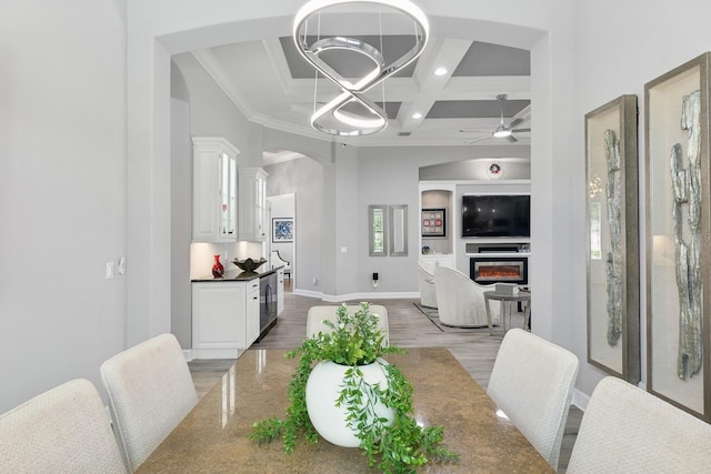 dining area featuring ceiling fan, baseboards, light wood-style floors, arched walkways, and coffered ceiling