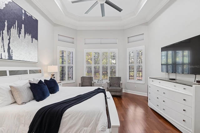 bedroom with a tray ceiling, baseboards, crown molding, and dark wood-type flooring