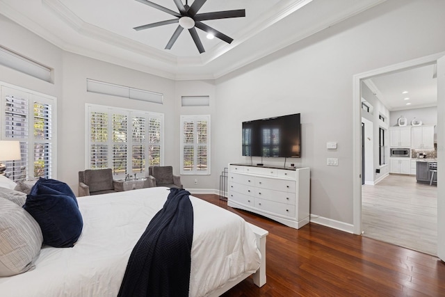 bedroom with hardwood / wood-style flooring, a raised ceiling, baseboards, and ornamental molding