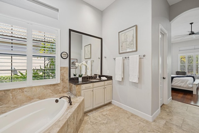 ensuite bathroom featuring a ceiling fan, connected bathroom, baseboards, a bath, and vanity