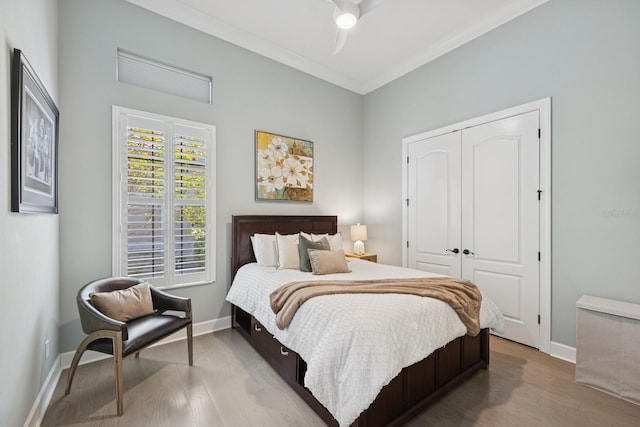 bedroom featuring a closet, baseboards, wood finished floors, and ornamental molding