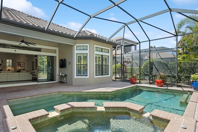 view of pool featuring a patio area, glass enclosure, a pool with connected hot tub, and ceiling fan