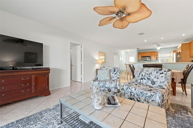 living area with light tile patterned floors, visible vents, baseboards, and a ceiling fan