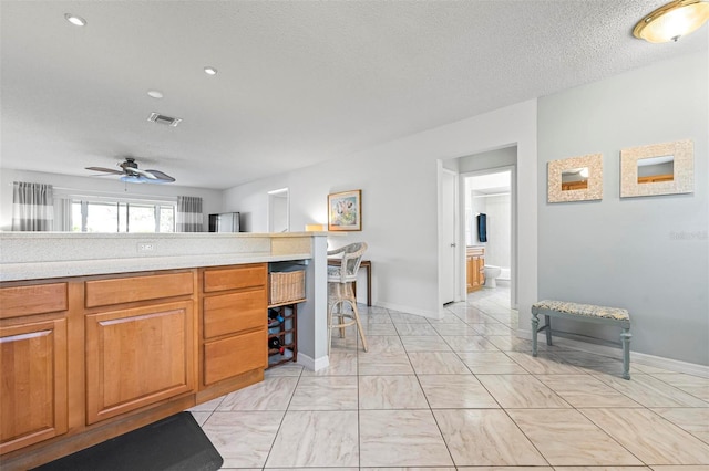 kitchen featuring visible vents, light countertops, brown cabinets, marble finish floor, and a textured ceiling