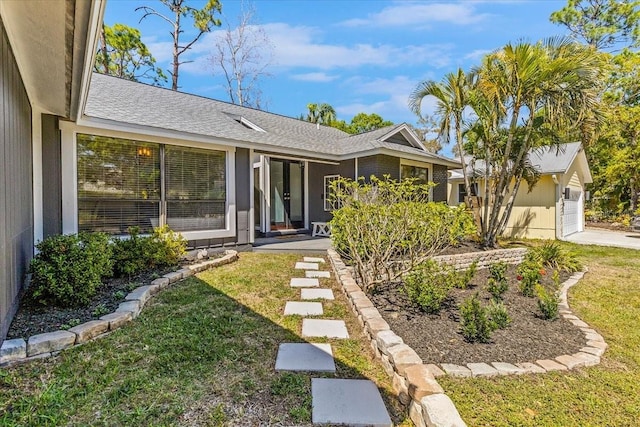 view of front of home featuring a front yard, a garage, and a shingled roof