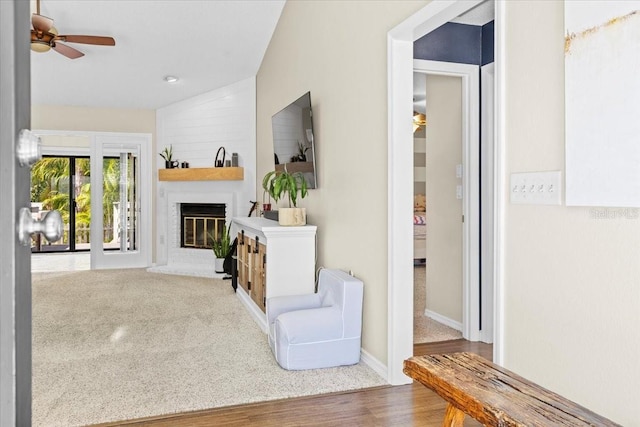 unfurnished living room featuring baseboards, ceiling fan, carpet flooring, a fireplace, and wood finished floors