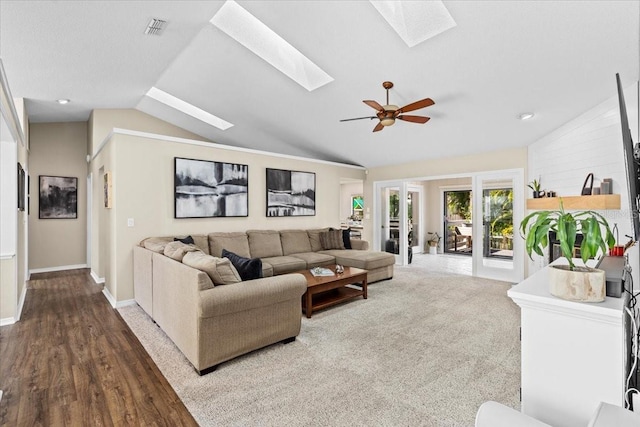 living area featuring wood finished floors, a ceiling fan, visible vents, baseboards, and lofted ceiling with skylight