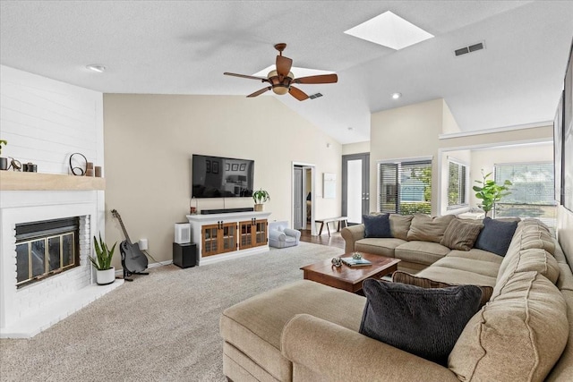 living area with visible vents, carpet, a fireplace, a skylight, and a ceiling fan