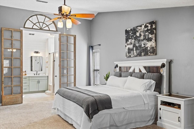 bedroom with a sink, connected bathroom, light carpet, and vaulted ceiling